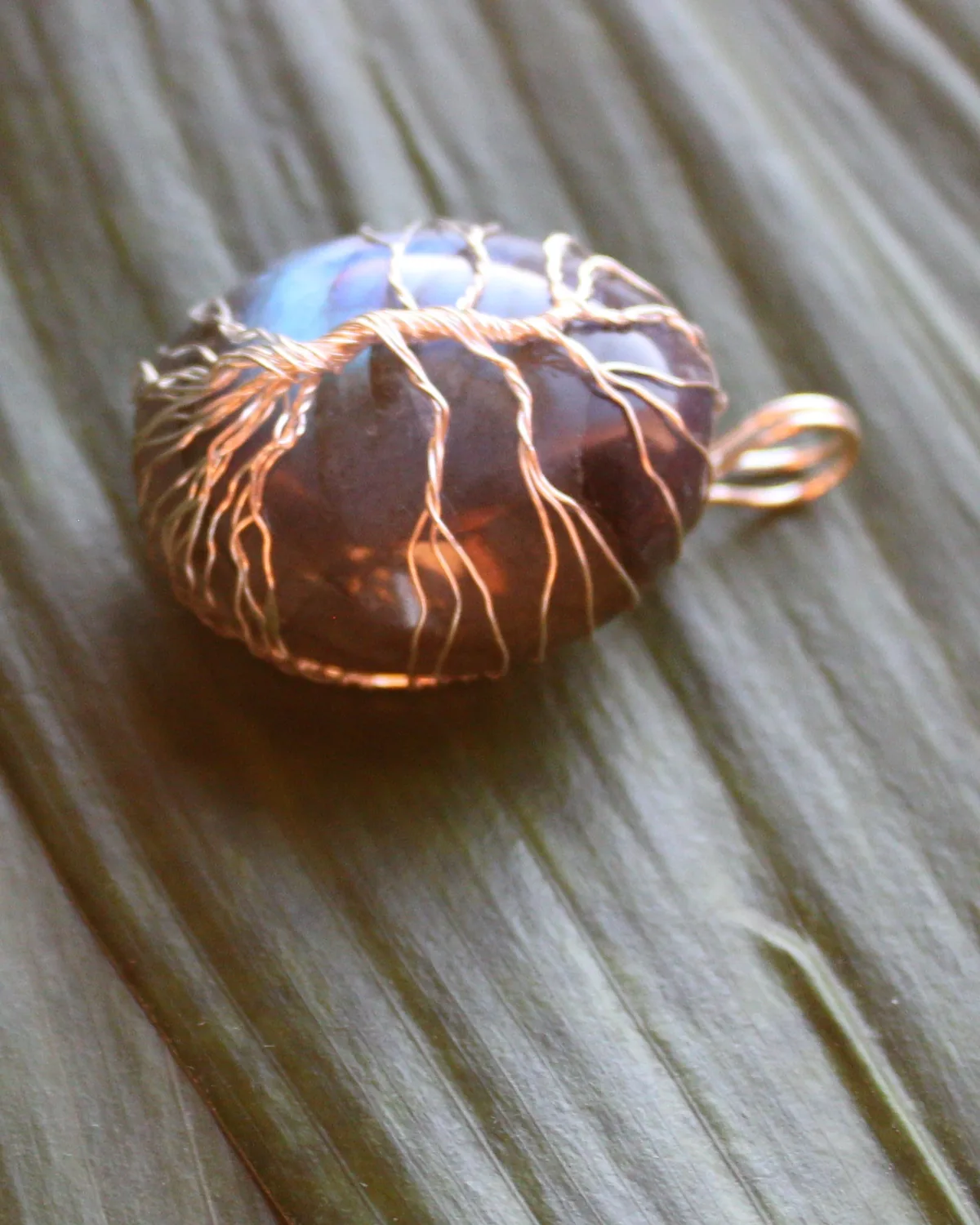 Close-up of copper wire roots wrapped around a labradorite stone